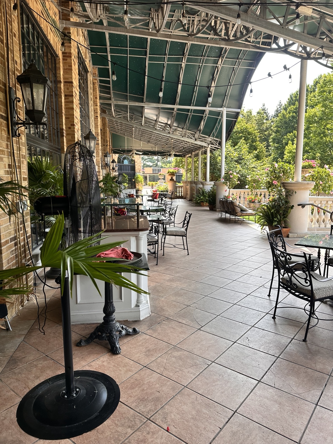 A covered terrace with greenery and café seating